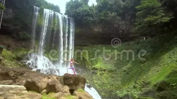 在瀑布旁的岩石上有一位金发女郎视频的预览图
