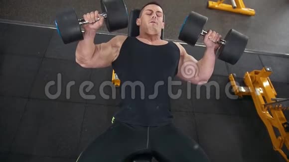 帅哥肌肉男在健身房做哑铃运动视频的预览图