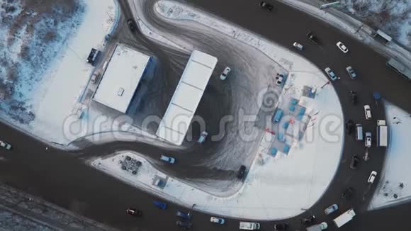 冬季城市设有加油站的环形道路上的空中旋转观景交通视频的预览图