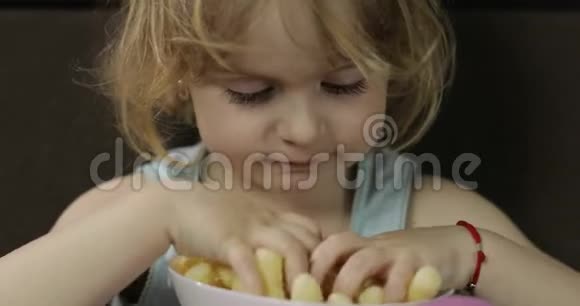女孩坐在沙发上吃玉米泡芙儿童微笑品尝爆米花视频的预览图