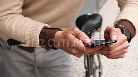 在智能手机上用单速自行车上网的时髦男人的双手紧握视频的预览图