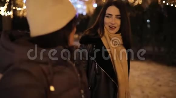 快乐的女孩沿着装饰着花环的夜巷散步聊天视频的预览图