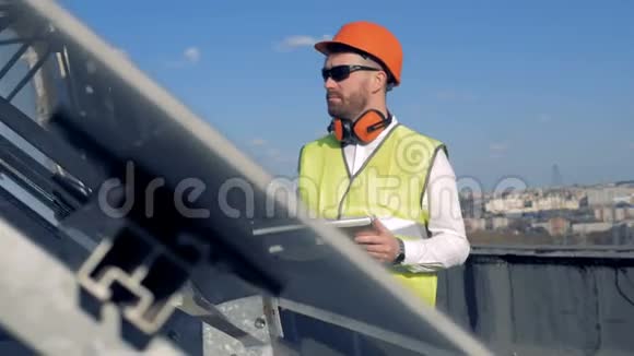 一个男人在屋顶上的小玩意上打字工人使用平板电脑同时检查太阳板是如何工作的视频的预览图