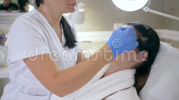 年轻化的过程美容师戴着带白色铅笔痕迹的手套女性皮肤上的问题区域视频的预览图