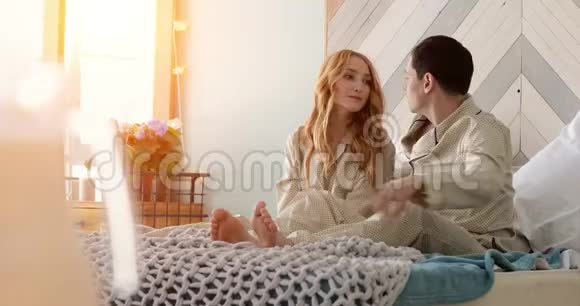 一对年轻的已婚夫妇在一个阳光明媚的早晨醒来视频的预览图
