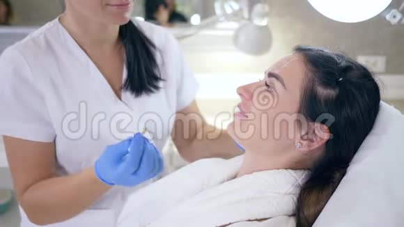 戴手套的医生在美容院用白铅笔给女孩脸上的问题区域做标记恢复活力视频的预览图