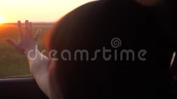 路旅游出行理念女孩挥手在窗户阳光下风在汽车慢动作视频黑发女郎视频的预览图