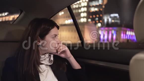 严肃的女商人从她的车后座看着一个夜城视频的预览图