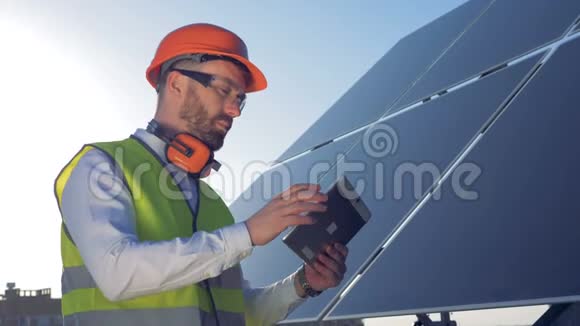 一个工人在他的平板上打字站在屋顶上的太阳板旁边4K视频的预览图