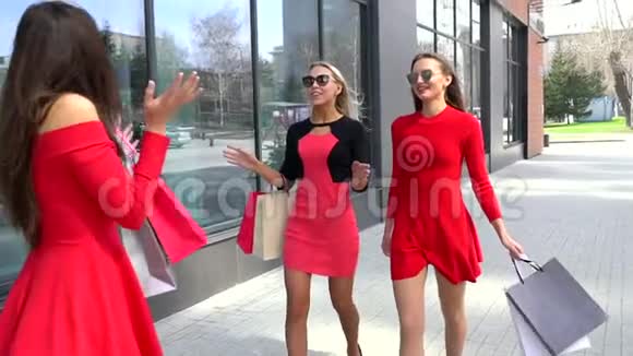 年轻的女朋友在购物的一天笑着有魅力的女性朋友用五颜六色的袋子走路的肖像视频的预览图