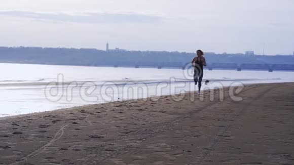 一个夏天的早晨穿着运动制服头发红的苗条中年妇女沿着沙质海岸奔跑视频的预览图