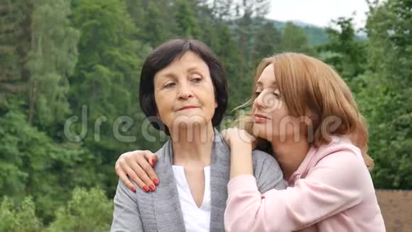 户外特写照片微笑的快乐的白种人高级母亲与她的成年女儿拥抱和看着她的成年女儿视频的预览图