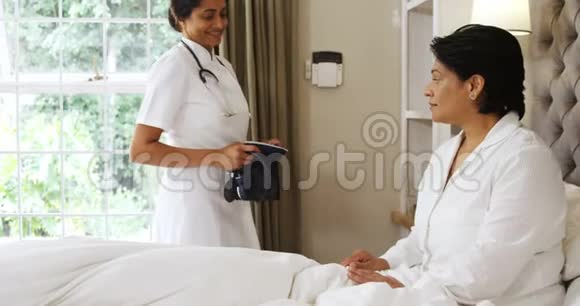 4k卧室测量成熟女性血压的女医生视频的预览图