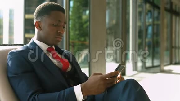 透视非裔美国商人在商务休息区休息时打电话视频的预览图