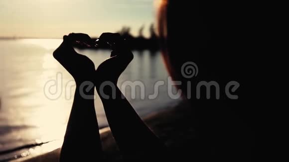 爱一个女孩在日落时用双手做一个美丽的心符视频的预览图