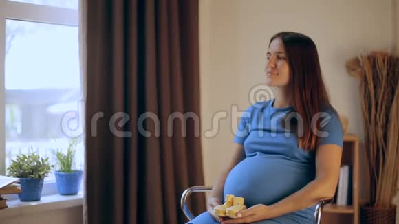 怀孕快乐的女人手里拿着婴儿鞋妈妈在等她的孩子孕妇的肚子怀孕生育观念视频的预览图