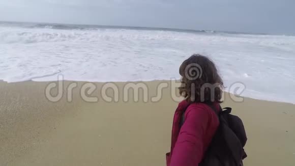 一个年轻的女人带着背包在海洋的背景下自拍视频的预览图
