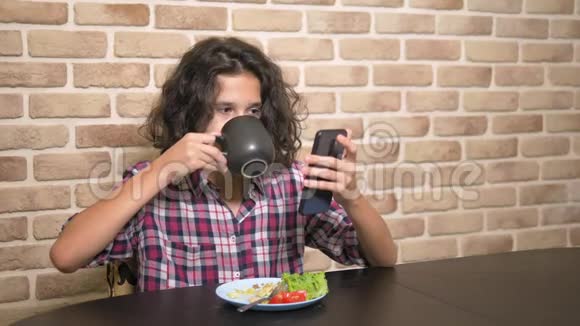 有胃口的饥饿少年在阁楼式的厨房里吃一个三明治里面有新鲜的生菜和西红柿视频的预览图