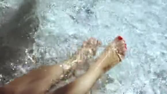 女人在游泳池里溅脚多莉拍了一个年轻的女人高兴地把她的脚喷在游泳池里视频的预览图