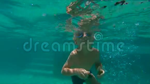 一个可爱的小男孩潜入游泳池在水下敲小石子拍了4倍视频的预览图