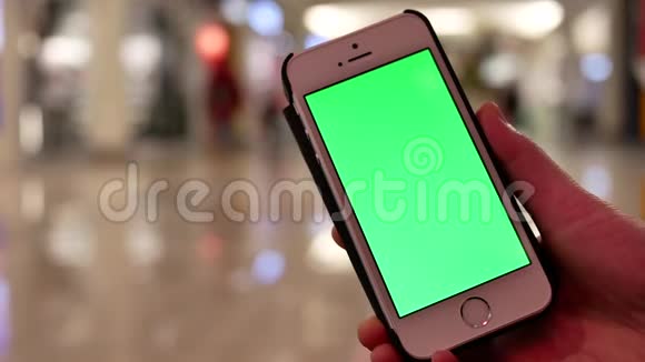 人们拿着绿色屏幕手机的运动与人们购物的模糊运动视频的预览图