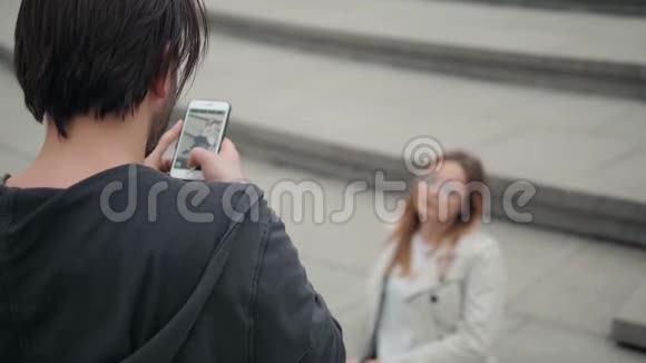 绿色公园里的一对情侣自拍男人打电话给女友拍照视频的预览图