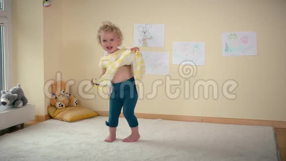 淘气的女孩在家里跑着跳着落在白色地毯上视频的预览图