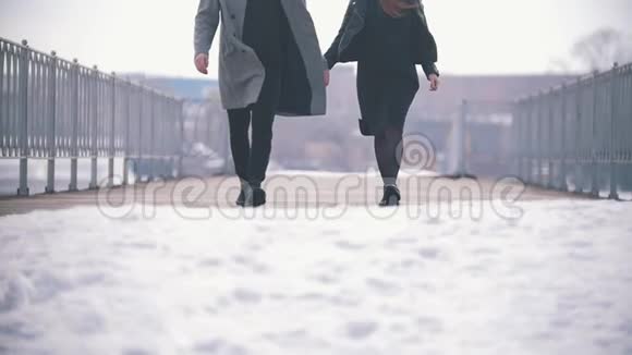 快乐的年轻夫妇在雪桥上奔跑慢动作视频的预览图