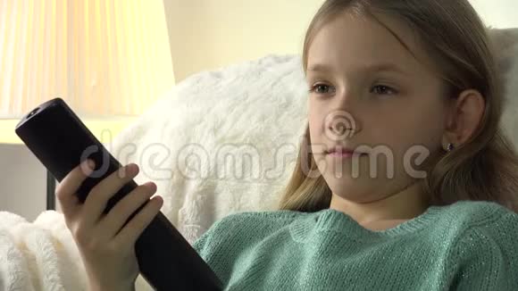 儿童肖像看电视小女孩脸微笑在沙发上放松教练视频的预览图