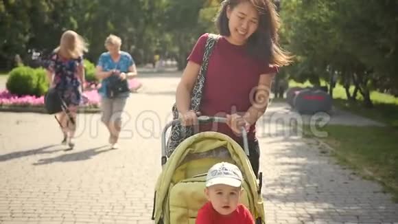 快乐妈妈和小孩子散步一位长相东方的美女带着孩子在城市公园散步慢慢视频的预览图