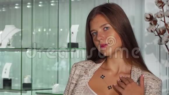 美丽的年轻女子照着镜子在珠宝店试穿一条项链视频的预览图