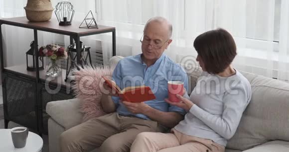 老年夫妇在沙发上看书和喝咖啡视频的预览图
