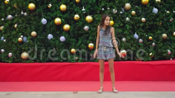 快乐的女孩在热带城市的圣诞树和棕榈树的背景下做体操空翻这就是视频的预览图
