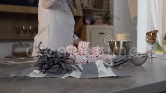 糖果店在时尚的厨房里把糖粉撒在盘子上的粉红色棉花糖上视频的预览图
