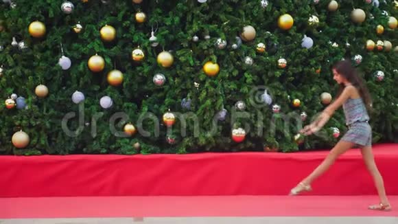 快乐的女孩在热带城市的圣诞树和棕榈树的背景下做体操空翻这就是视频的预览图