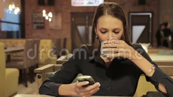 有智能手机的年轻女子在咖啡厅喝咖啡视频的预览图