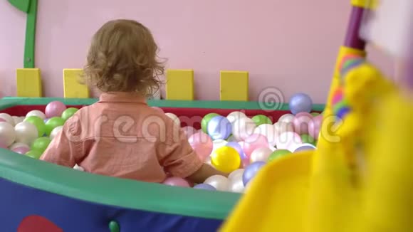快乐的白种人可爱的金发孩子玩得很开心在多种颜色的球池里玩学前教育视频的预览图