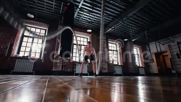 一个在健身房训练的人用绳子在地板上训练他的手视频的预览图