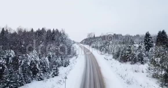 鸟瞰飞越高速公路冬季道路之间的雪林视频的预览图