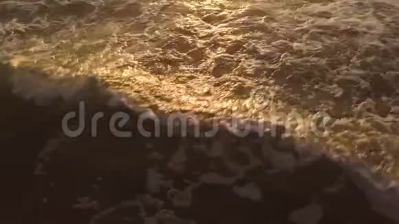 海水在沙滩上波浪而金色的日出在夏天的早晨在傍晚的天空中人们可以看到美丽的日落视频的预览图