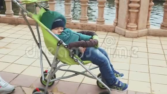 1岁的男婴睡在婴儿车里在旅途中睡着了慢动作视频的预览图