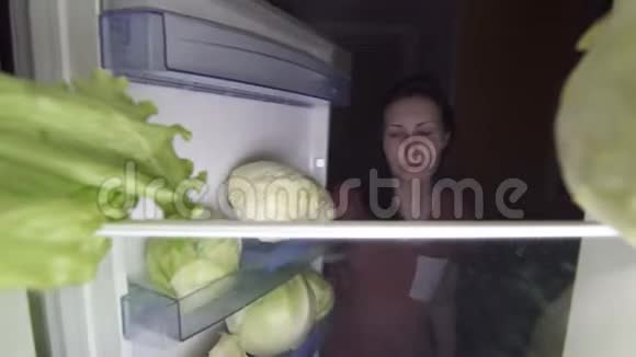 悲伤的女孩晚上打开冰箱看着食物上的食物视频的预览图