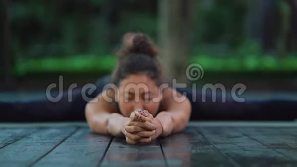 年轻女子有东方的外表独自在热带岛屿的木制甲板上练习瑜伽女孩视频的预览图