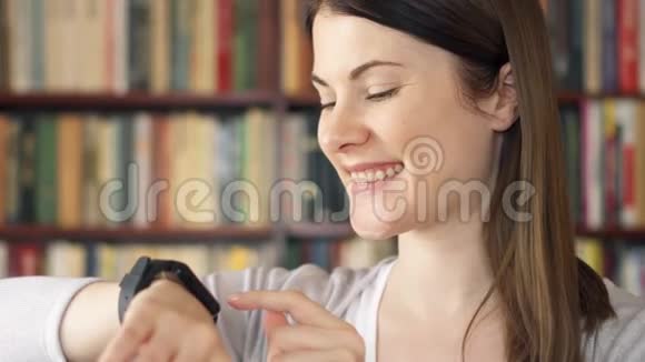 女大学生在图书馆使用智能手表浏览阅读与朋友聊天视频的预览图