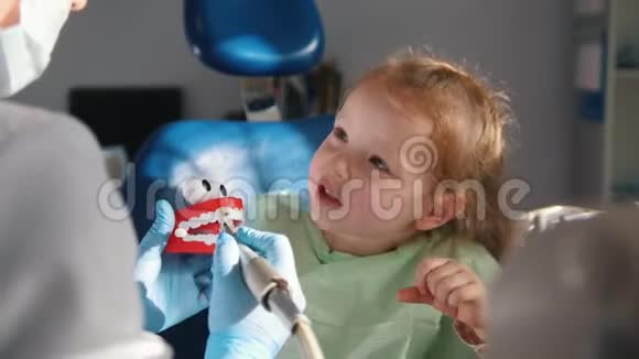 一个坐在牙科椅上听牙医解释即将刷牙程序的小女孩视频的预览图