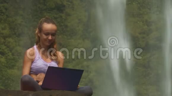 女孩微笑打开笔记本电脑开始打字瀑布视频的预览图
