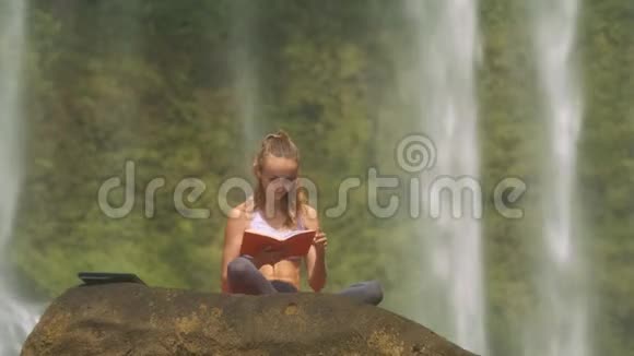 少女阅读瀑布飞流背后的植物视频的预览图