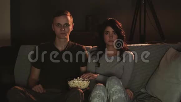 年轻夫妇在家看电视吃爆米花视频的预览图