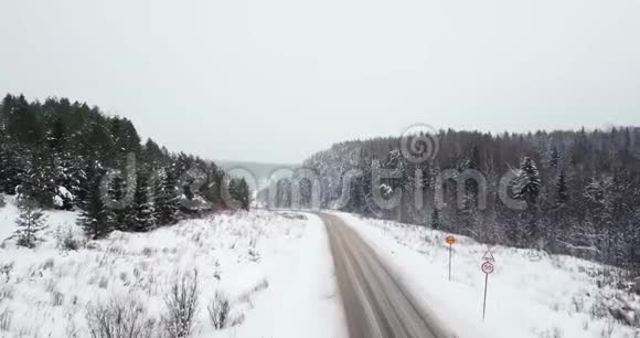 鸟瞰飞越高速公路冬季道路之间的雪林视频的预览图