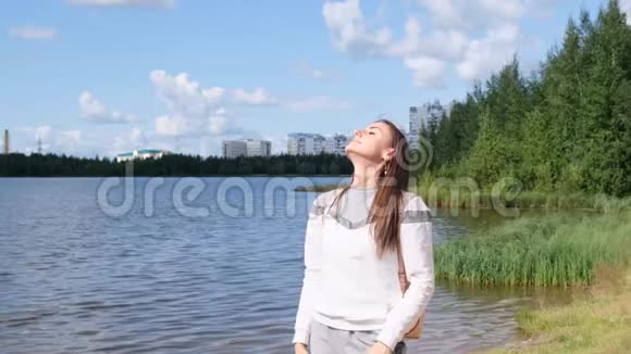 张开双手的女孩自然自由一个女孩站在那里享受美丽的阳光一个女孩站在水边视频的预览图